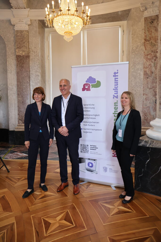 Portrait von Frau Hofmann, Prof. Dr. Timm Albers, Marion Lepold vor einem Kinder.Sprachen.Zukunft. Roll-Up.